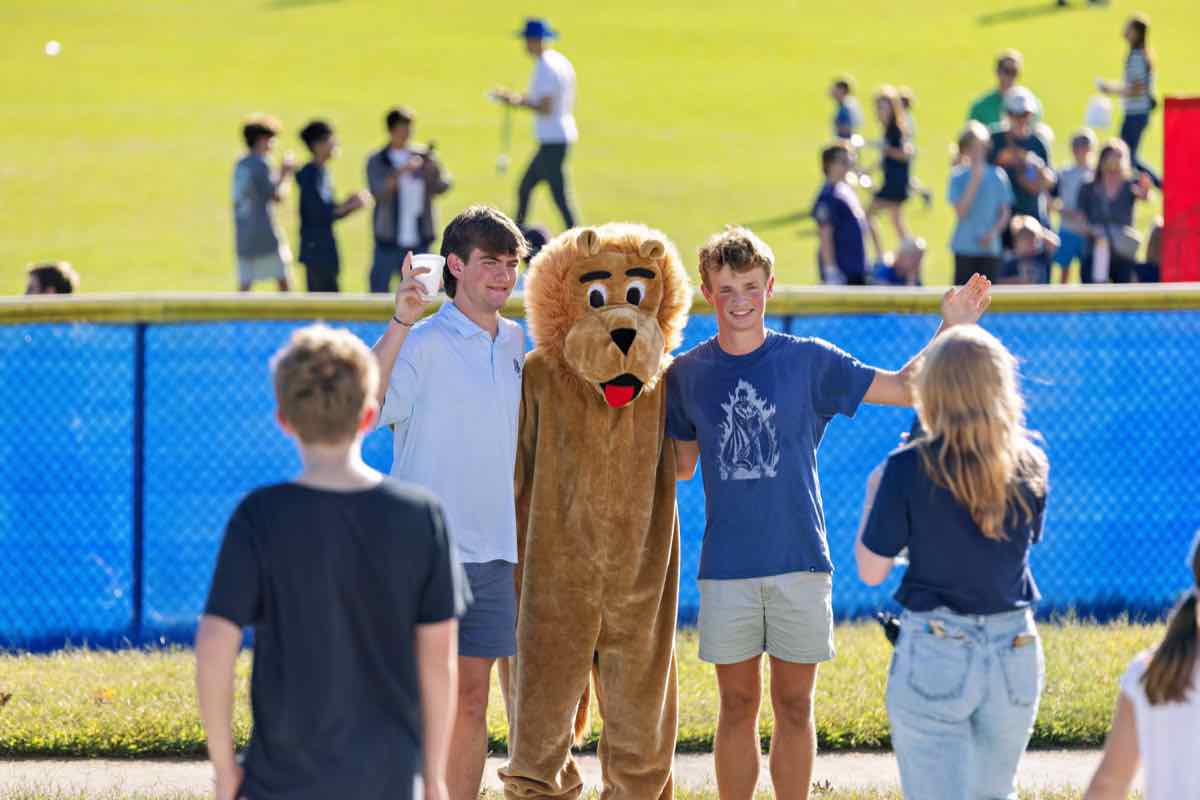 Two students posing with Leo the Lion mascot beside the field
