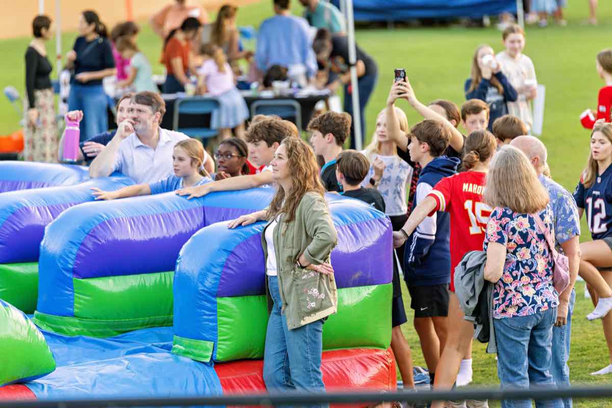 Families gathered around an inflatable obstacle course